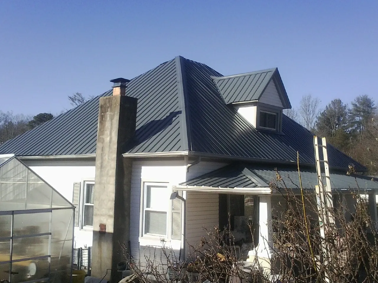 Dark blue standing seam metal roof on a white farmhouse with dormer — Slate & Tile Roof Repair by Roofing Brothers in Maysville